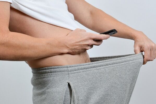 A man stares at an enlarged penis in his pants